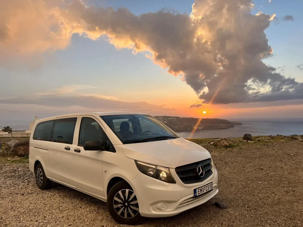 White Mercedes Vito in Santorini on caldera cliff with volcano background