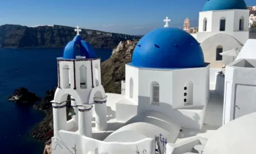 Beautiful Blue Domes in Oia, Santorini with white crosses and Therasia Island in the background