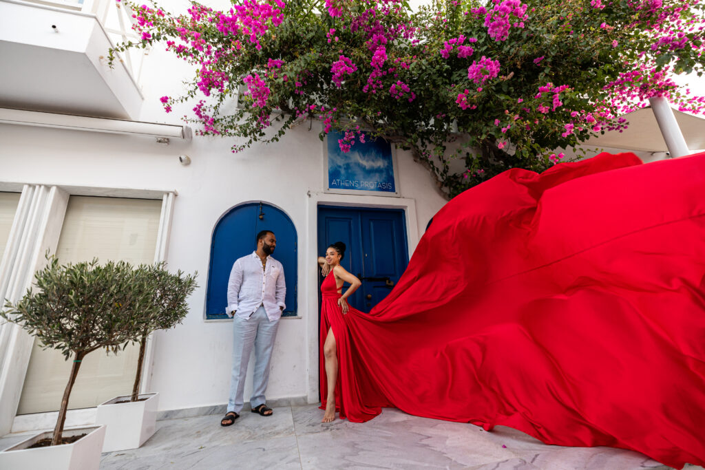 Santorini Flying dress photography with red color dress and blue doors and flowers